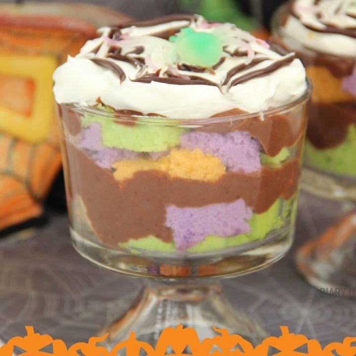 Mini Halloween Trifles - Layers of fun colored cake with pudding and topped off with some spider-webbed whipped cream! It's a super fun dessert for your kids or grandkids, and it's really quick to put together!