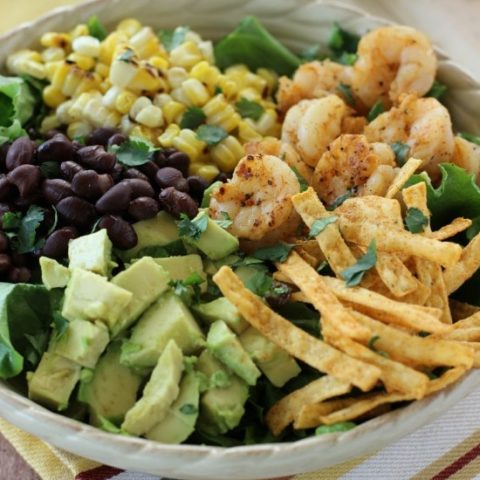 Southwest Shrimp Salad - Grilled shrimp and corn, black beans, diced avocado, and crispy southwest tortilla strips piled onto a bed of green leaf lettuce and topped with a mexi-ranch dressing.