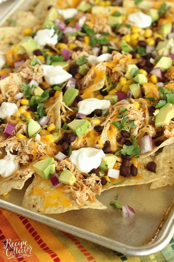 Slow Cooker Chicken Nachos - Chicken breasts cooked with a homemade salsa in the slow cooker, black beans, corn, red onion, and diced avocados piled on corn tortilla chips and broiled to create an easy Mexican dinner!