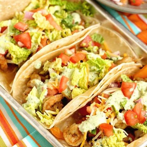 Ultimate Shrimp Tacos - Seasoned shrimp sauteed with peppers, and onions wrapped in a tortilla and topped with pico de gallo, cilantro dip, cheese, and napa cabbage.