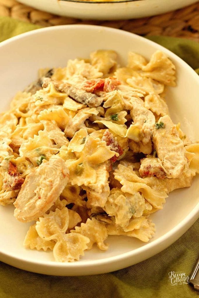 Copycat Spicy Romano Chicken Pasta - Make this creamy restaurant-style chicken pasta made with bow-tie noodles, sun-dried tomatoes, artichoke hearts, mushrooms, and grilled chicken tossed in a creamy dreamy sauce.